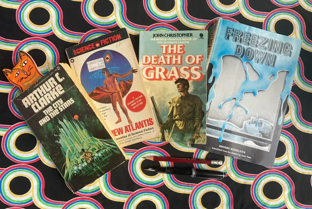 Arthur C. Clarke’s The City and the Stars (1956), Robert Silverberg edited The New Atlantis (1975), John Christopher’s The Death of Grass (1956),  Anders Bodelsen’s Freezing Down (1969, trans. 1971).
Clarke cover: Man approaches massive city. Cat bookmark pokes out. New Atlantis Cover: Man stands and gestures with a desert behind him. Christopher cover: Man stands with gun.  Bodelsen cover: Ice drips down around a man laying below. Arthur C. Clarke’s The City and the Stars (1956), Robert Silverberg edited The New Atlantis (1975), John Christopher’s The Death of Grass (1956),  Anders Bodelsen’s Freezing Down (1969, trans. 1971).
Clarke cover: Man approaches massive city. Cat bookmark pokes out. New Atlantis Cover: Man stands and gestures with a desert behind him. Christopher cover: Man stands with gun.  Bodelsen cover: Ice drips down around a man laying below.