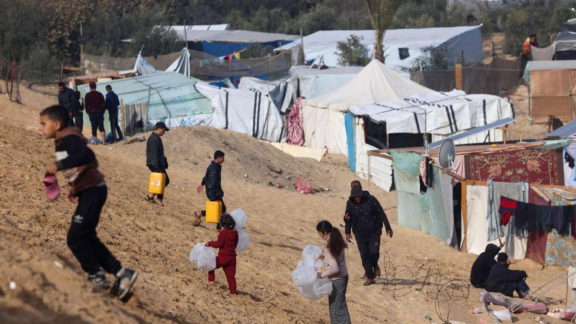 Palestinos desplazados llevan botellas vacías a un camión de agua de MSF en Tal Al-Sultan, un barrio de Rafah. Foto: MSF/ Mohammed Abed (©)